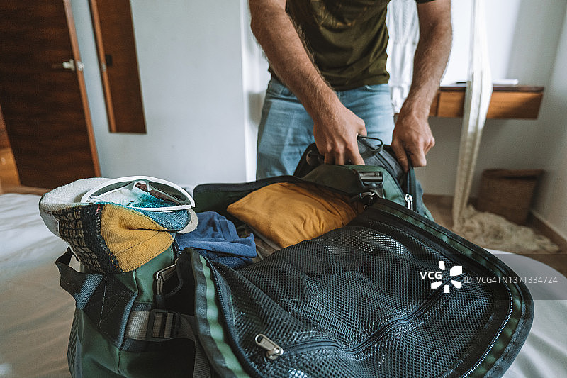 男旅行者打包行李将衣服放入行李袋图片素材
