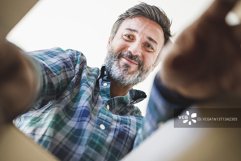 面带微笑的中年男人正在查看纸箱图片素材