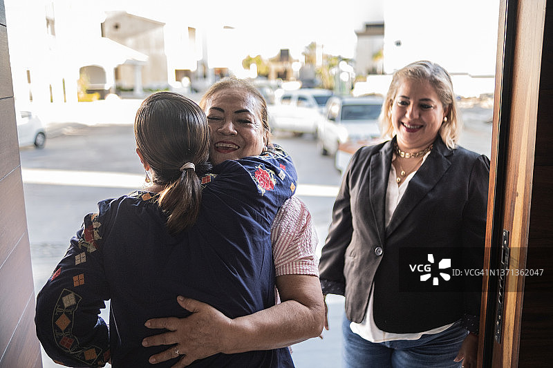 年长的拉丁女人在家欢迎朋友图片素材