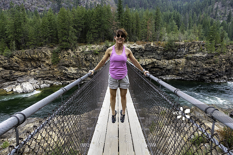 女人在蒙大拿州库特内瀑布悬索桥顶部的栏杆旁图片素材