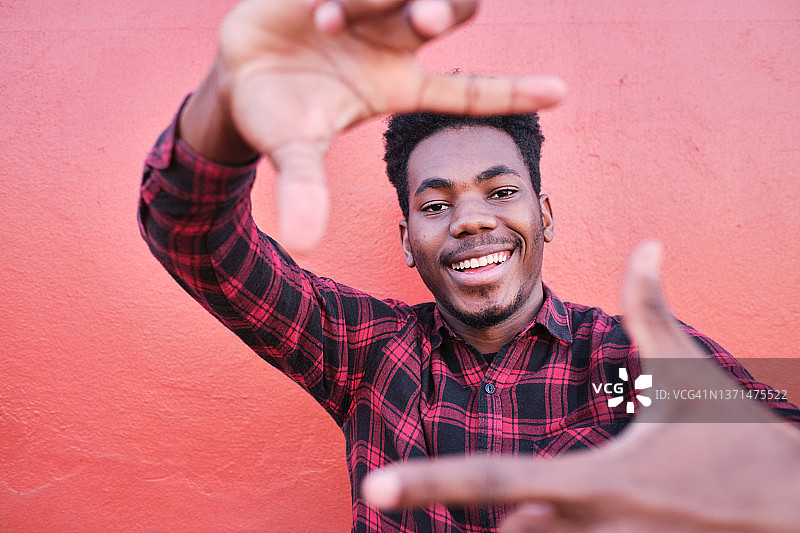 微笑并用手向相机做取景手势的年轻男人图片素材