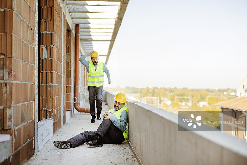 工人在建筑工地帮助受伤的同事图片素材