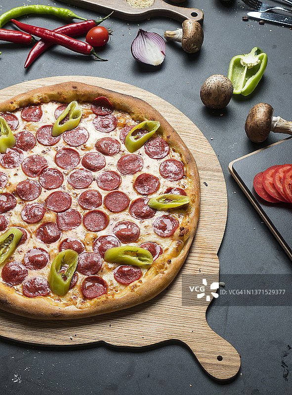 意式风味披萨，配萨拉米香肠、奶酪、辣椒、大蒜和新鲜香草图片素材