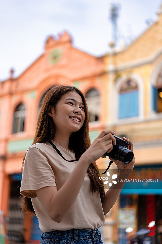 使用相机拍摄风景的亚洲年轻背包客，享受快乐的夏季假期图片素材