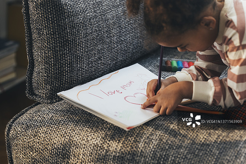 一个可爱的非洲裔美国儿童为母亲节准备惊喜的侧面照图片素材