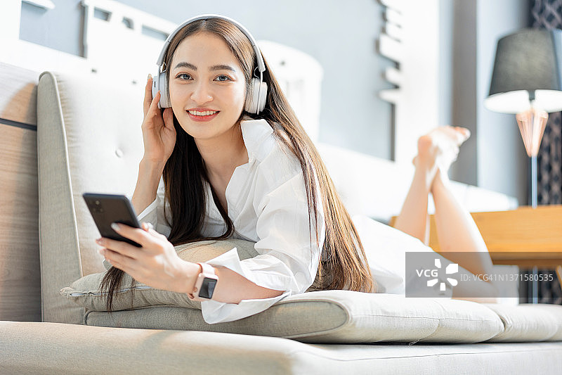 在客厅听音乐的亚洲年轻女子图片素材