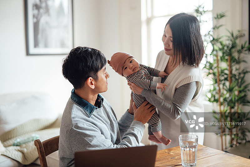 年轻父母在家工作时照顾宝宝图片素材