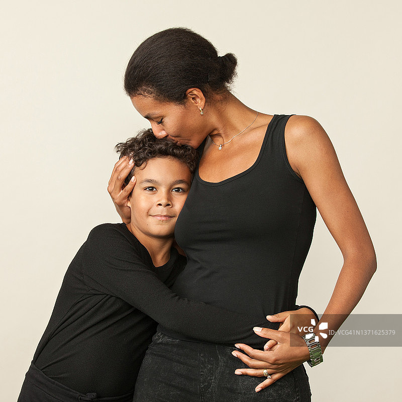 米色背景上的母亲和儿子影棚肖像图片素材