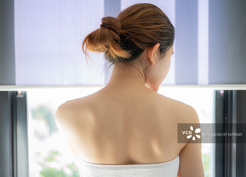 年轻亚洲女子浴后裹浴巾背影图片素材