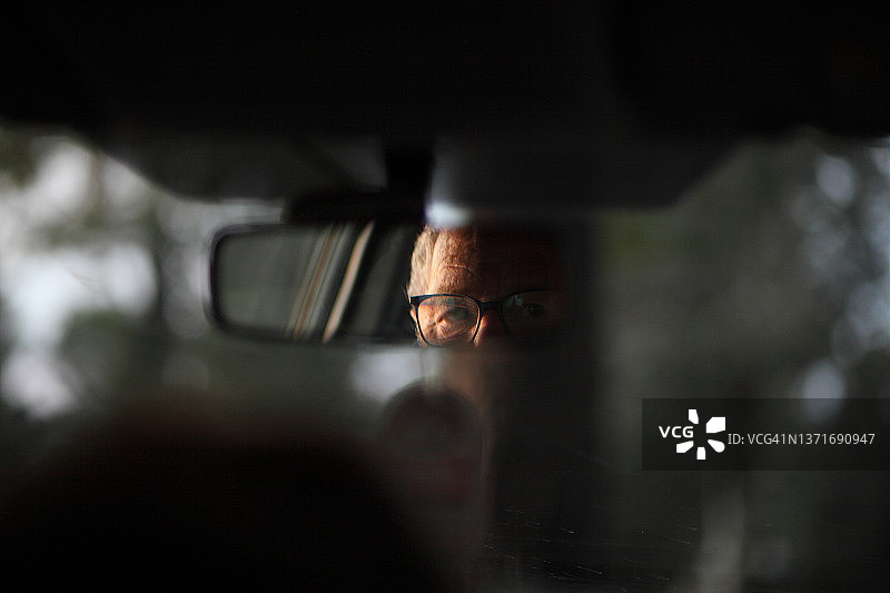 日落时分，车镜中男人的半张脸和眼镜图片素材