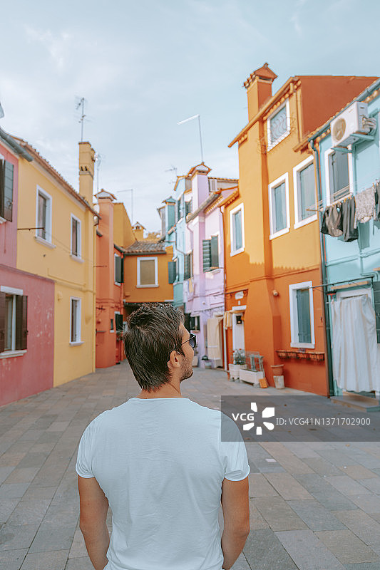 走在意大利威尼斯布拉诺镇街道上的年轻游客男子背影图片素材