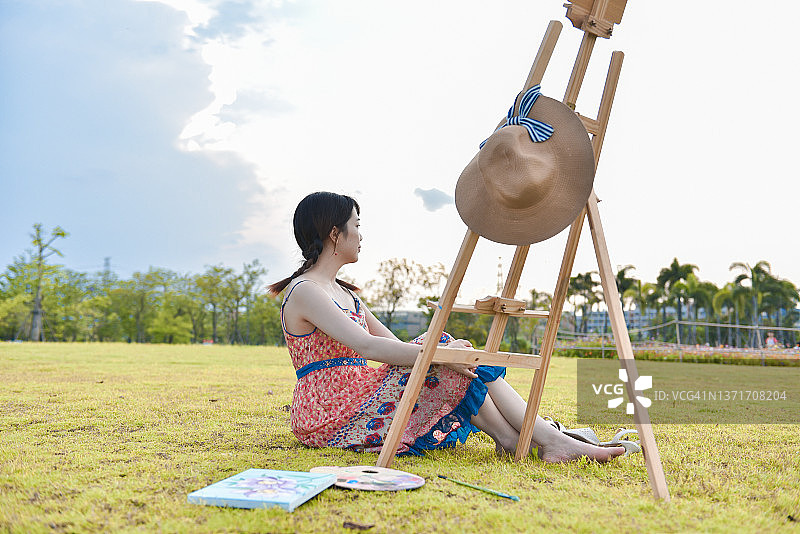 优雅的亚洲女画家（25-29岁）坐在中国广东省江门市的公园草地上休息图片素材