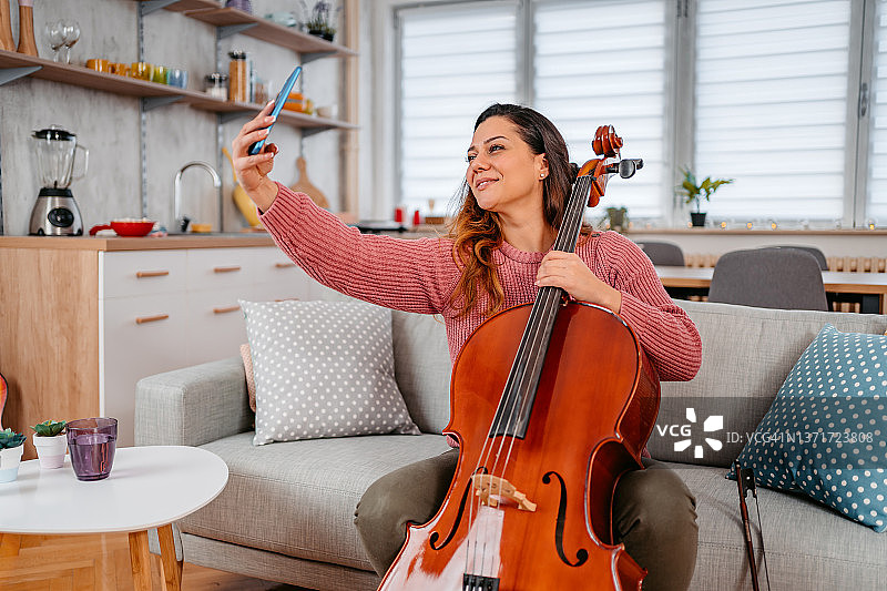 年轻音乐家拿着大提琴自拍图片素材