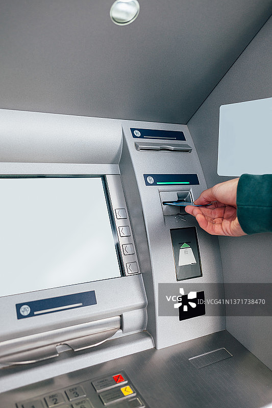 男人在ATM机上插入银行卡图片素材