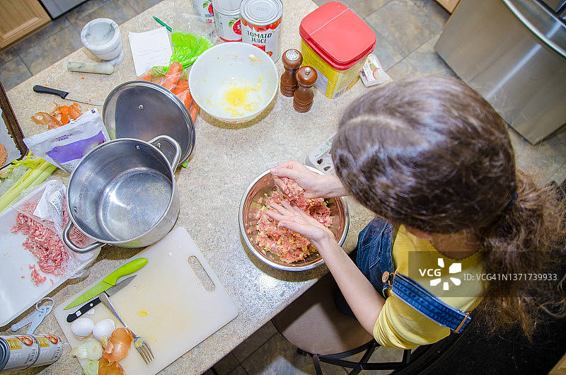 女孩将鸡蛋和洋葱与生肉混合图片素材