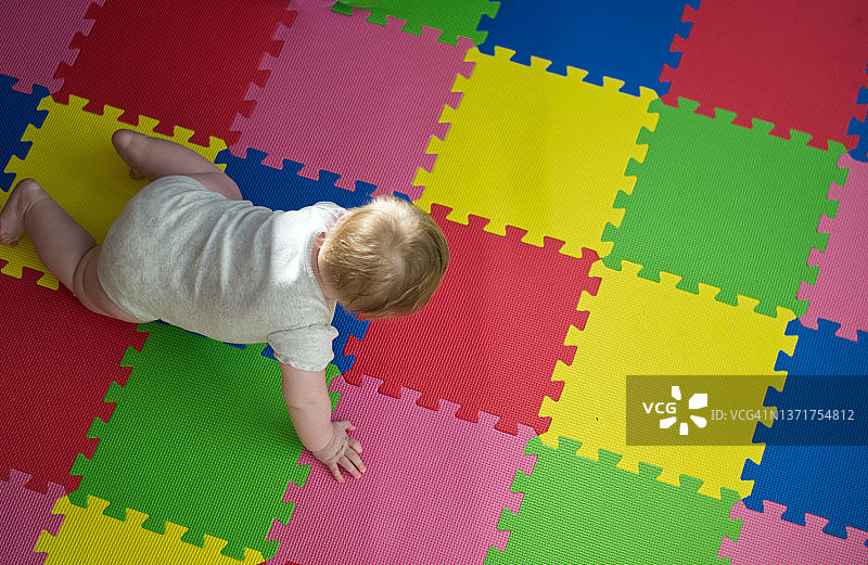在彩色垫子上爬行的宝宝图片素材