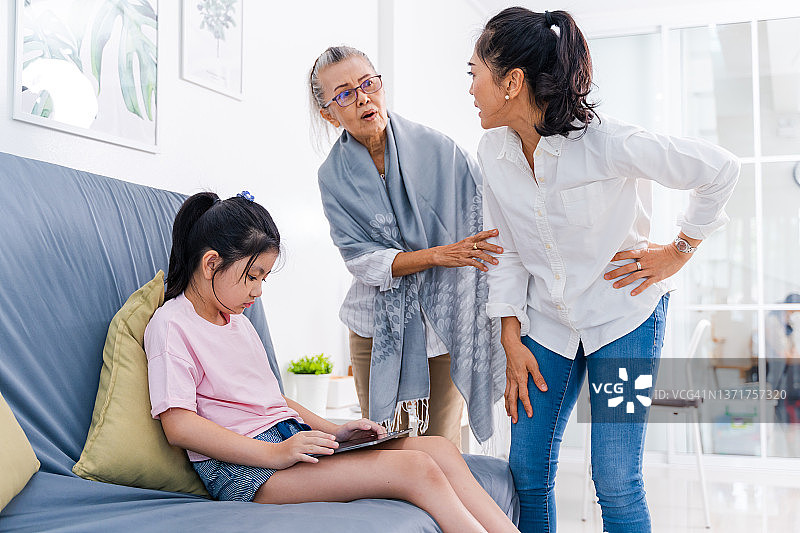 愤怒的母亲斥责在家玩平板电脑的不听话的孩子图片素材