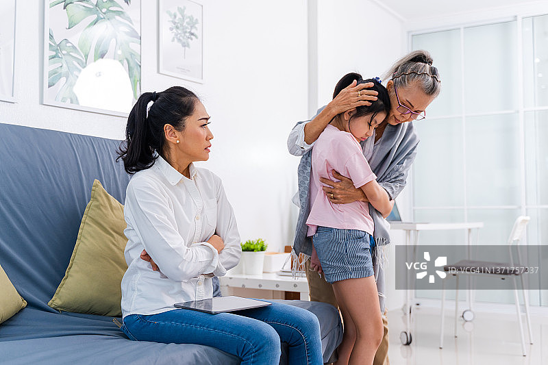 愤怒的母亲斥责在家玩平板电脑的不听话的孩子图片素材