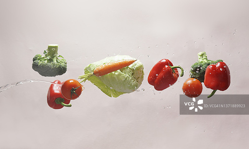 浅米色背景上飞溅着水的飞行蔬菜图片素材