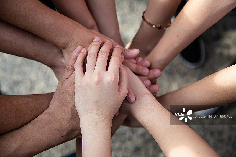 人们手叠在一起支持年轻人图片素材
