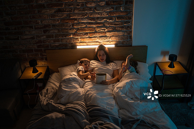 母亲给孩子们读睡前故事图片素材