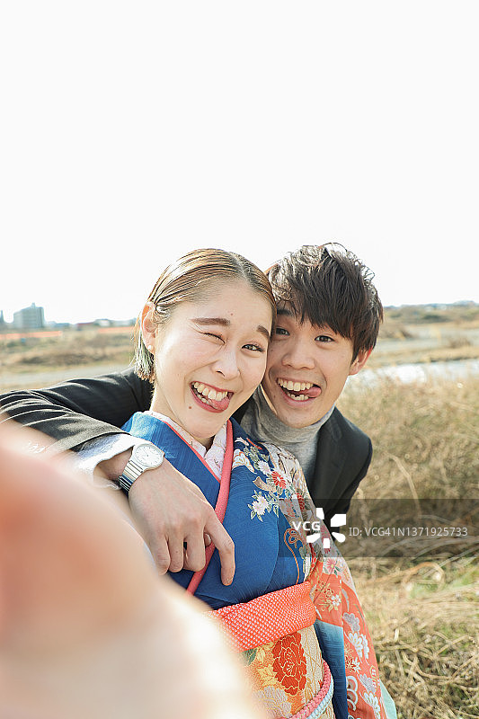 年轻的日本情侣用智能手机自拍图片素材