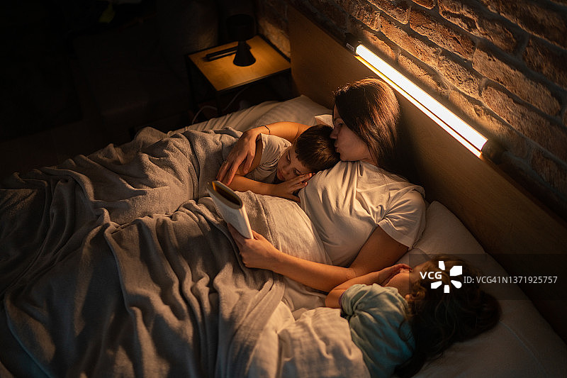 母亲在孩子们睡前给他们讲故事图片素材