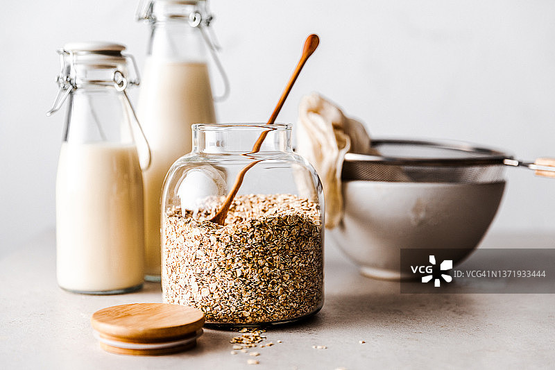 玻璃罐中的燕麦、燕麦奶瓶和桌上的大碗图片素材