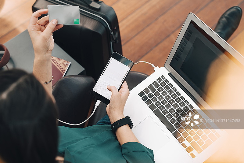 女商人拿着信用卡在机场使用手机（高角度）图片素材