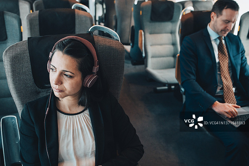 与商人一起在火车上使用耳机旅行的女商人图片素材