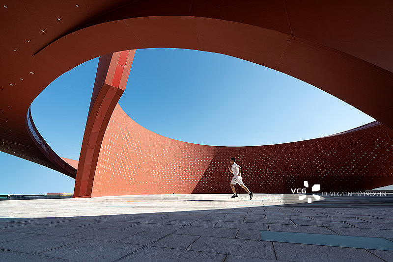 在红色弯曲抽象建筑空间中奔跑的人图片素材