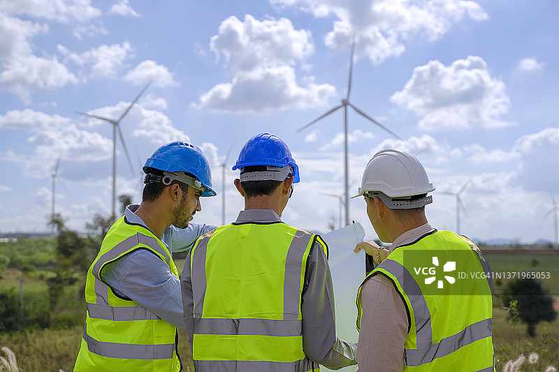 在电力工地的蓝领工人与风车图片素材