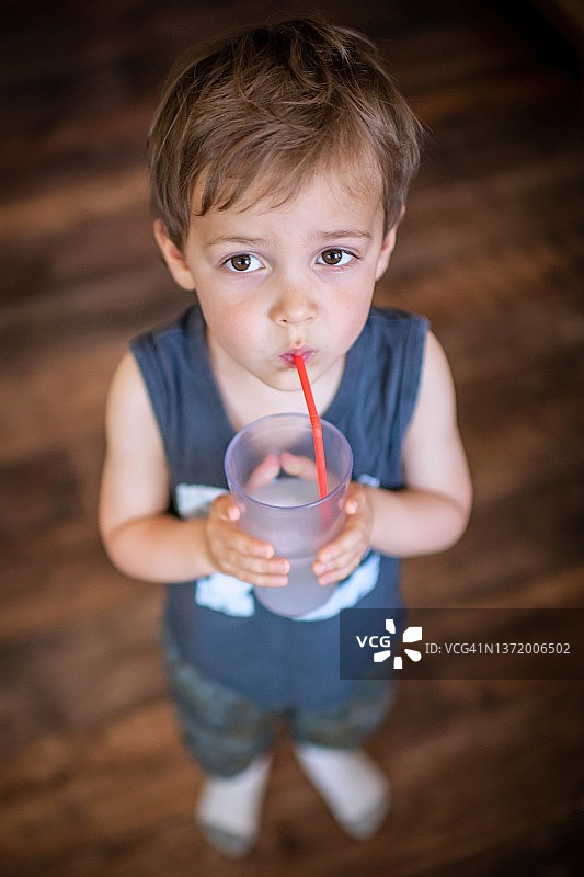 若有所思的男孩用塑料吸管喝水图片素材