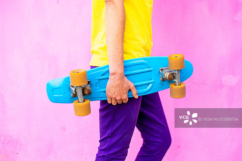 女人手持蓝色复古滑板的身体特写图片素材