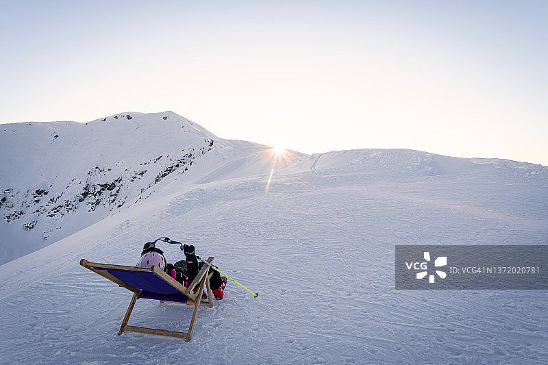 穿着滑雪服的孩子们在冬天躺椅上放松图片素材