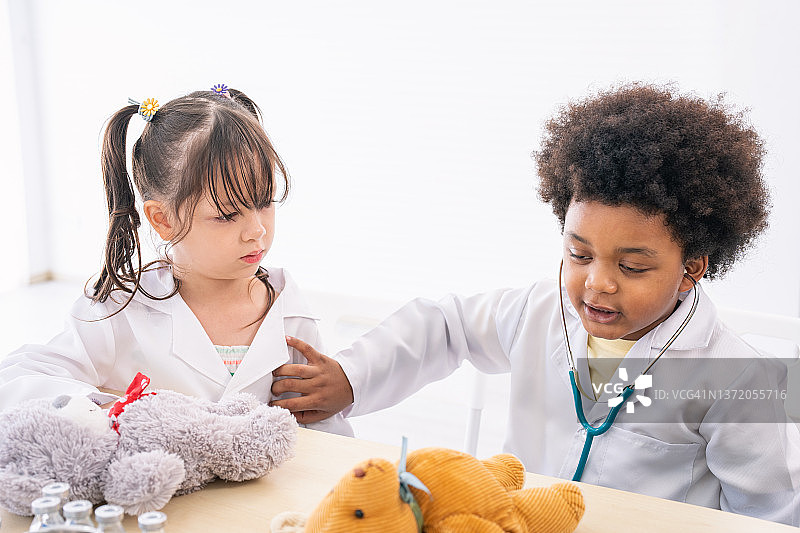 穿着医生服装的男孩和玩听诊器的女孩图片素材