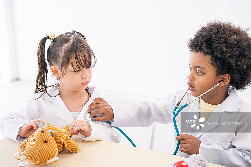 穿着医生服装的男孩和玩听诊器的女孩图片素材