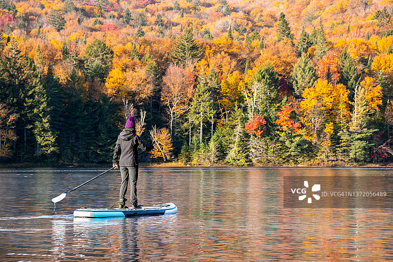 女人在加拿大魁北克省翠湖山国家公园秋季的湖上划桨板图片素材