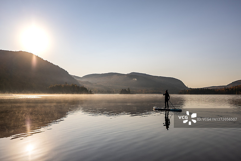 女人在加拿大魁北克省翠湖山国家公园秋季的湖上划桨板图片素材