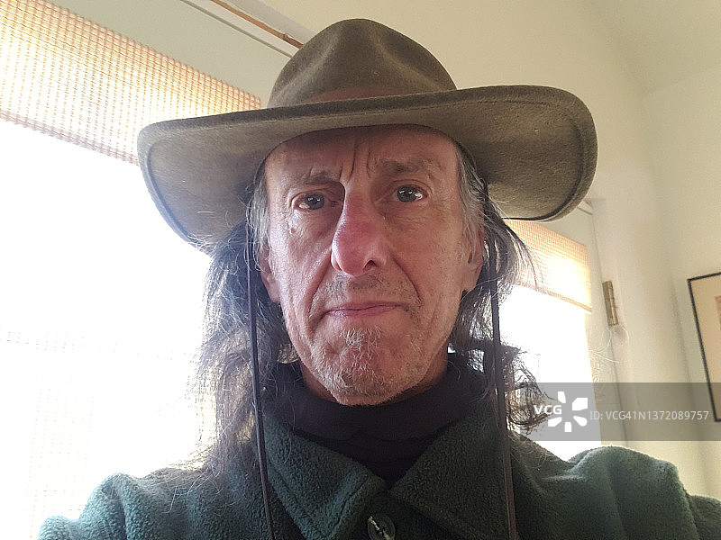戴帽子的老年男人在室内看镜头图片素材