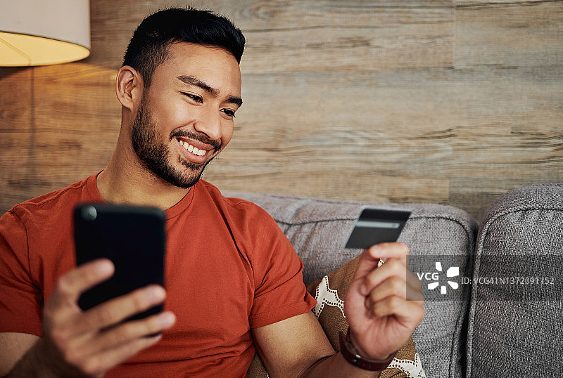 独自坐在客厅用手机网购的年轻男人照片图片素材