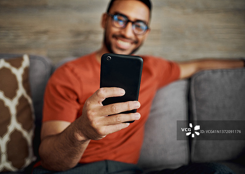 年轻男子独自坐在客厅里使用手机图片素材