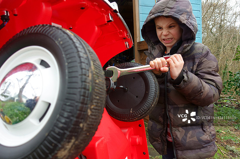 男孩用扳手修理玩具车图片素材
