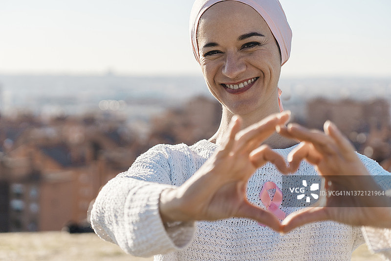 微笑的女人用粉红丝带用手比心图片素材
