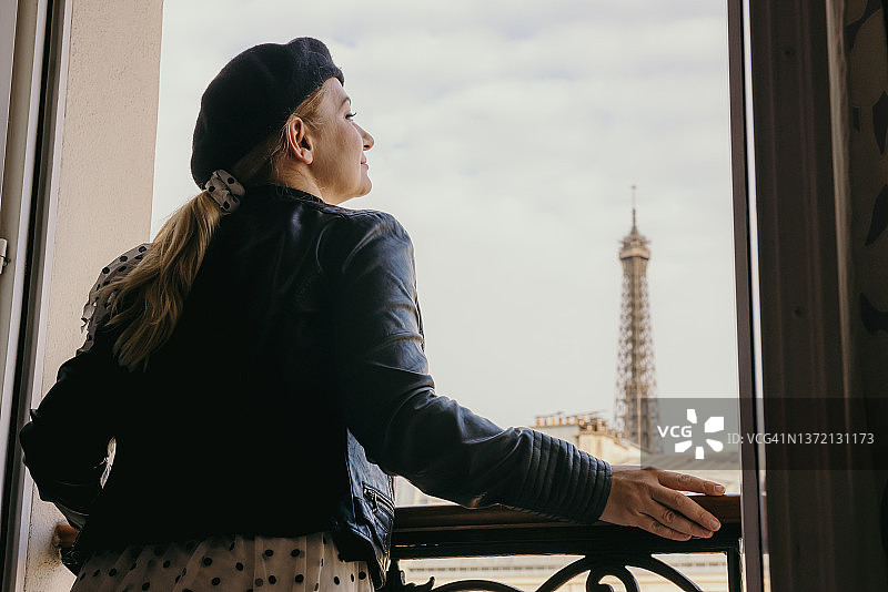 穿着时尚服装的女人在巴黎酒店房间窗边微笑图片素材