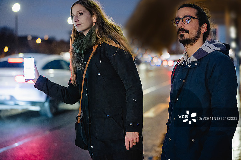 傍晚，情侣在巴黎埃菲尔铁塔前用手机上的标志试图拦出租车图片素材