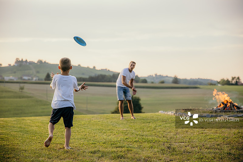 夏日篝火旁，父亲和儿子在乡间玩飞盘图片素材
