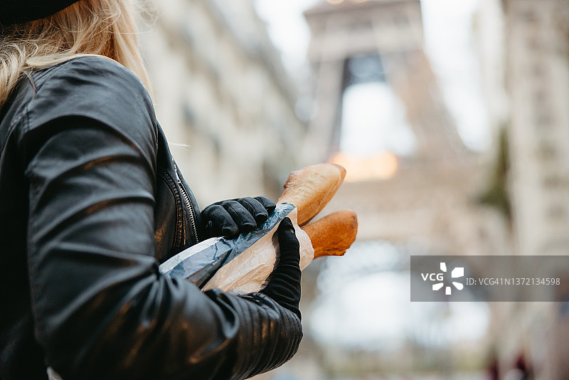 女子手持法棍，背景为巴黎埃菲尔铁塔特写图片素材