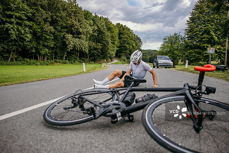 受伤的自行车手痛苦地坐在路上图片素材