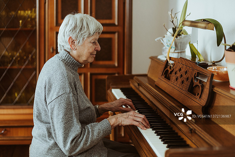 一位老年妇女正在家里弹钢琴图片素材